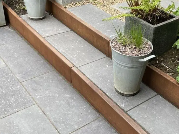 Structural backing of a corten steel retaining wall during soil backfilling.