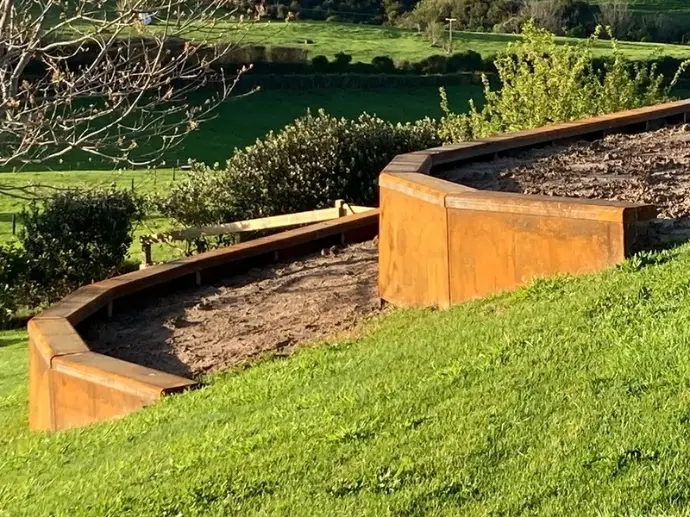 Leveling steel retaining wall panels in a narrow side-passage garden.