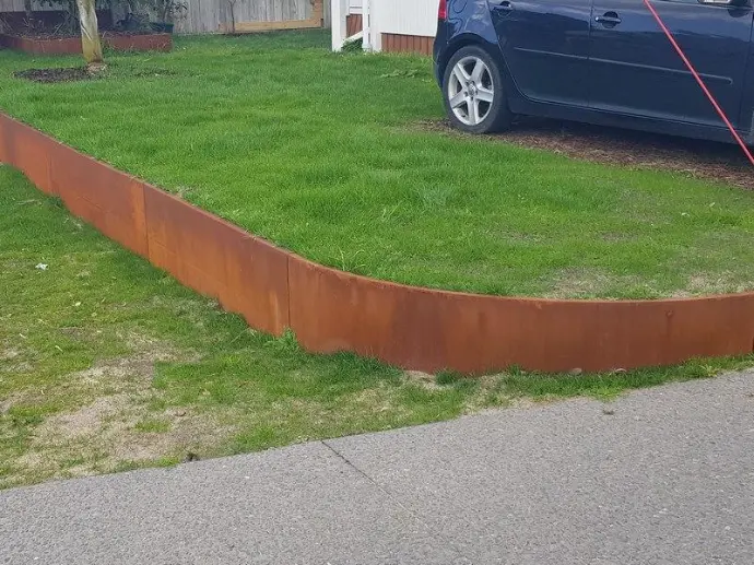 Raised vegetable garden beds built from steel retaining wall panels.