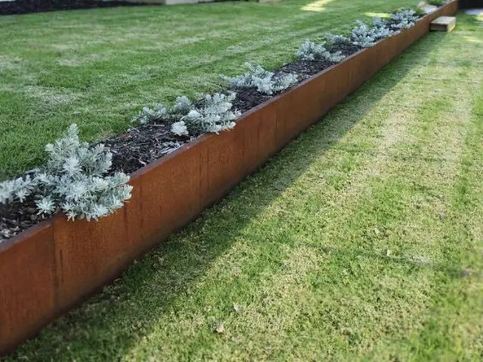 Comparison of new grey steel vs weathered corten steel retaining wall panels.