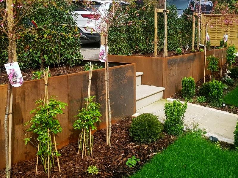 Modern front yard featuring low-profile metal retaining walls and gravel.