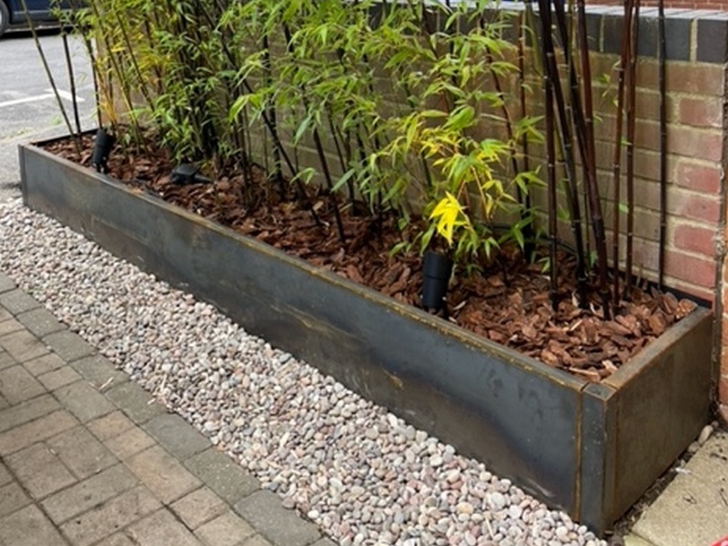 3 sided corten planter against brick wall